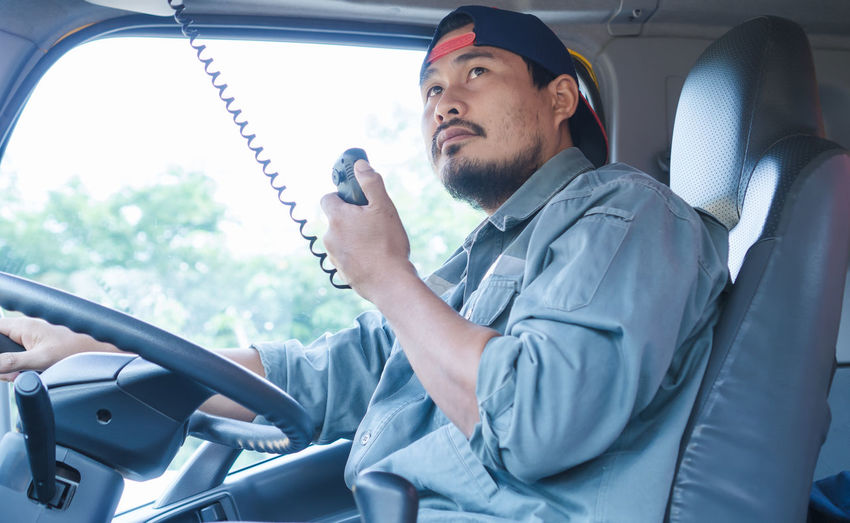 Driver holding walkie-talkie while sitting in truck