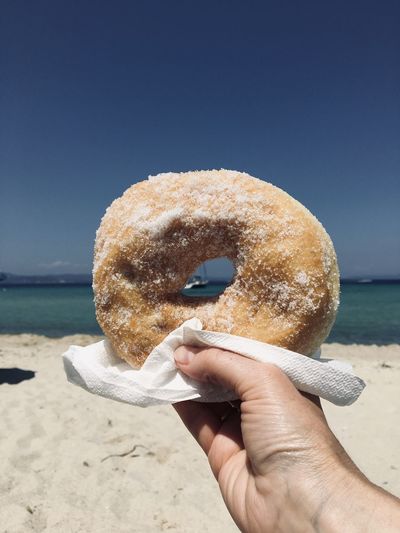 Person holding donut on beach
