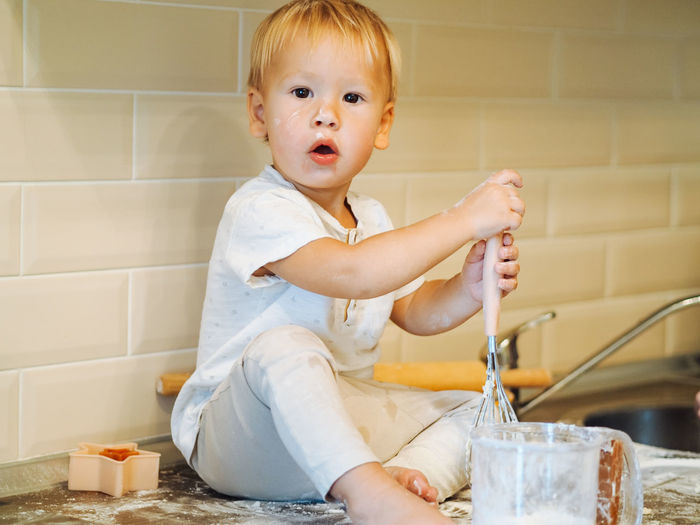 Portrait of boy preparing food while sitting on kitchen