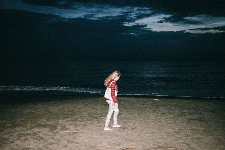 Girl standing on beach against sea