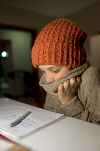 Boy wearing knit hat studying at home