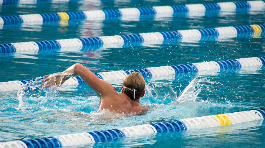 Rear view of man swimming in pool