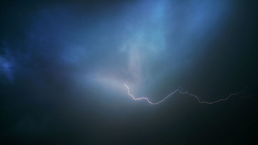 Low angle view of lightning against cloudy sky at night