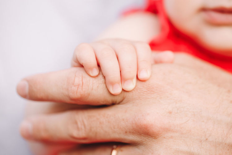 Closeup of baby fingers holding father parent hand palm. baby trust and confidence in adult parent