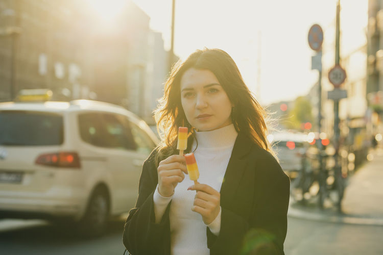 Thoughtful woman holding flavored ice in city