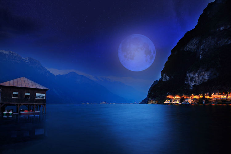 Scenic view of sea against mountains at night