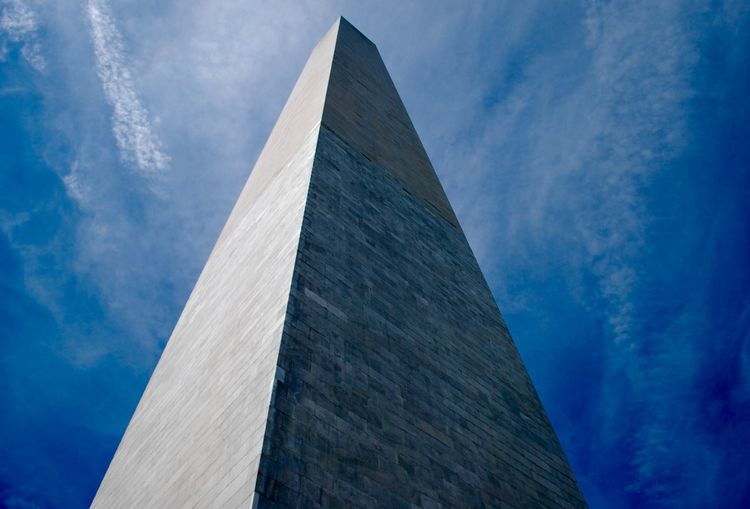 Low angle view of washington monument against cloudy blue sky on sunny day