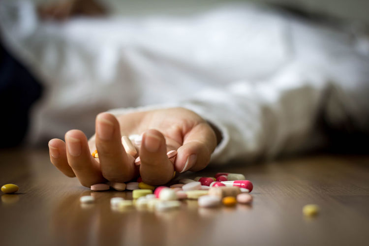 Close-up of person with pills lying on floor