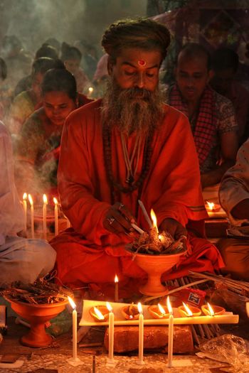 Saint praying at rakher upobash infront of burning candle and incense