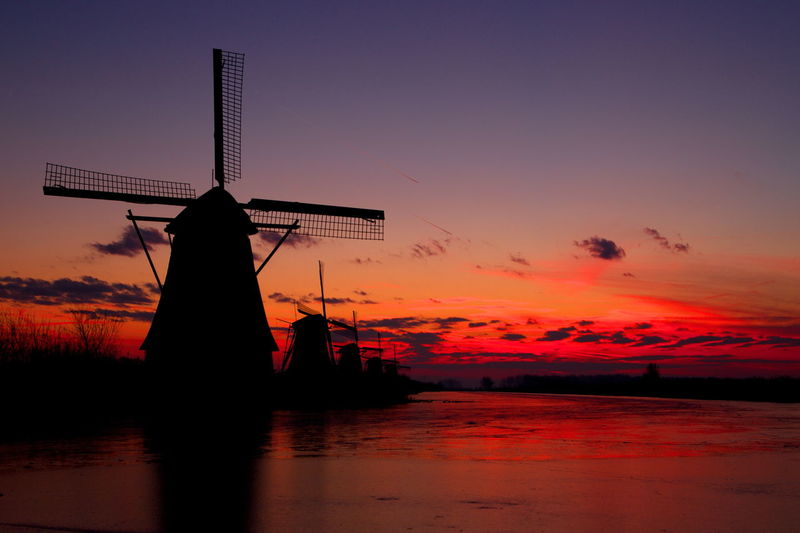 Silhouette windmill against romantic sky at sunset