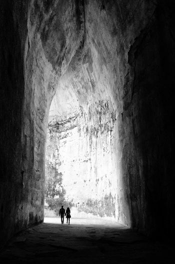 Silhouette couple walking in cave