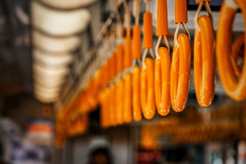 Close-up of orange handles hanging in train