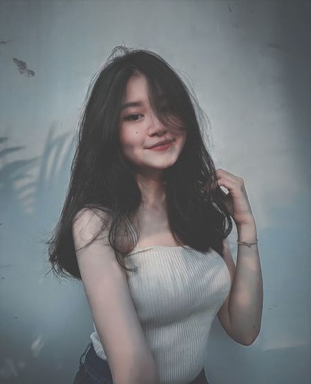 Portrait of smiling young woman standing against wall