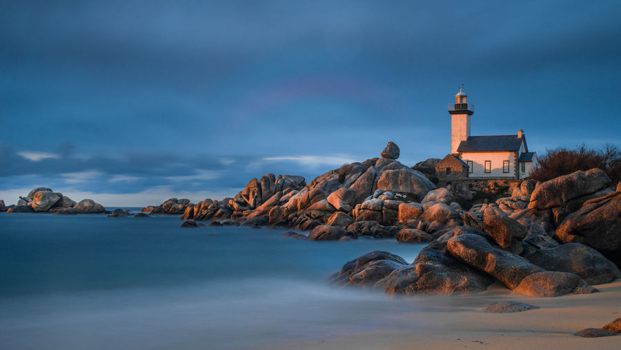Lightouse phare de pontusval in sunset glow with rocks ans beach in foreground