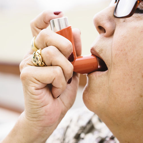 Close-up of woman using inhaler