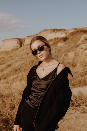 Young woman wearing sunglasses standing on land