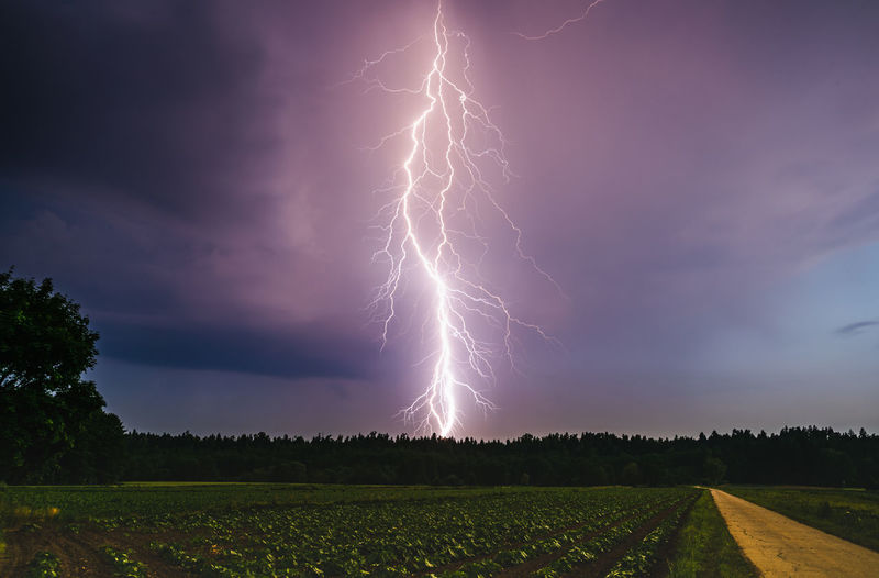 Lightning bolt at night over rural area. agriculture fields.