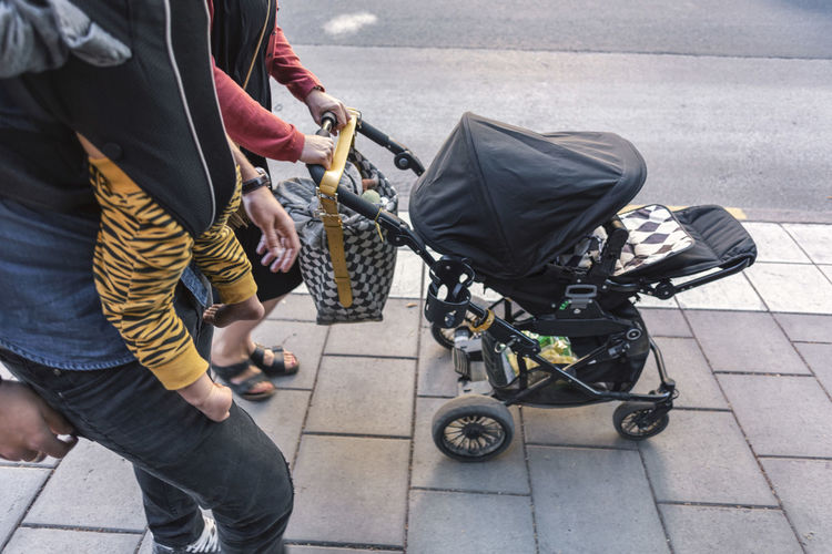 Parents with baby boy and stroller walking on sidewalk