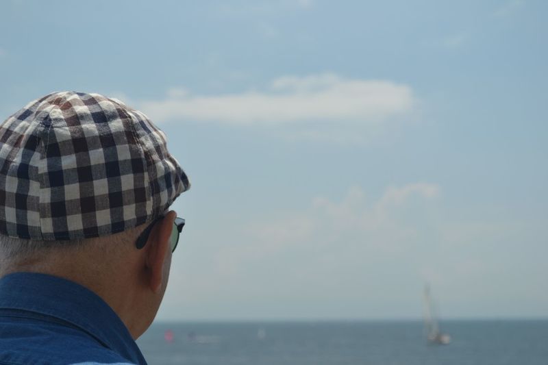 Close-up of man looking at sea against sky