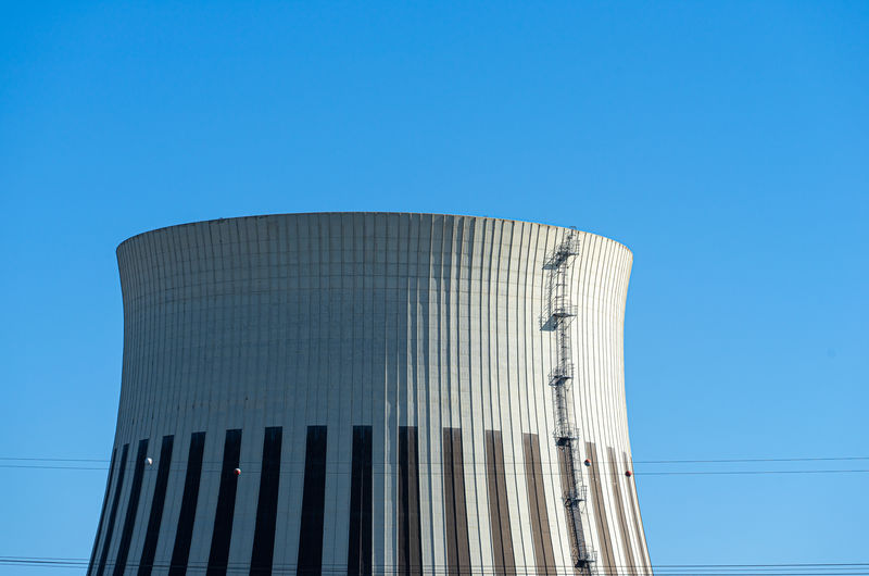 Low angle view of cooling tower against clear blue sky