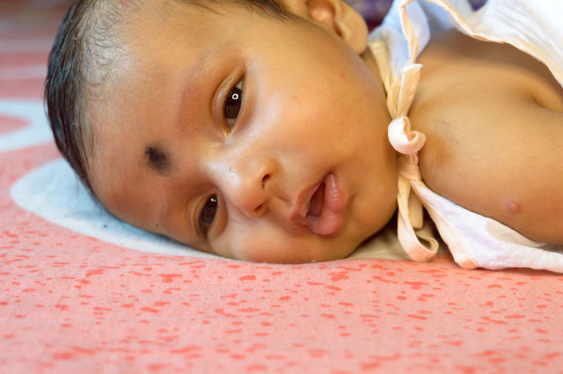 Close-up portrait of cute baby lying on bed