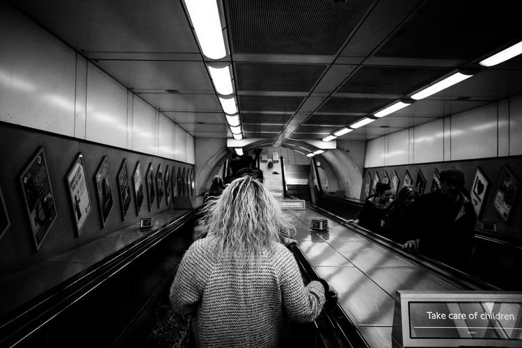 Rear view of woman on escalator at subway