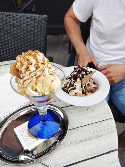 Midsection of man holding ice cream on table