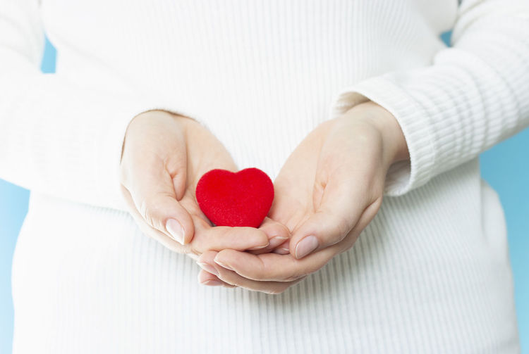Midsection of woman holding heart shape with hands