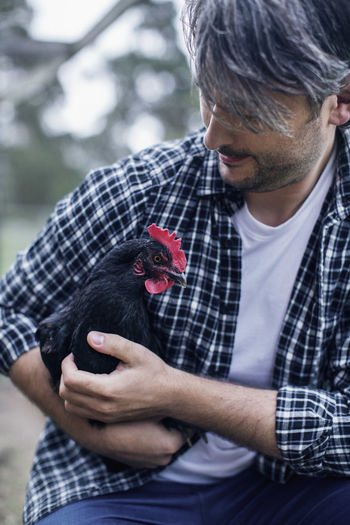 Man carrying hen at poultry farm