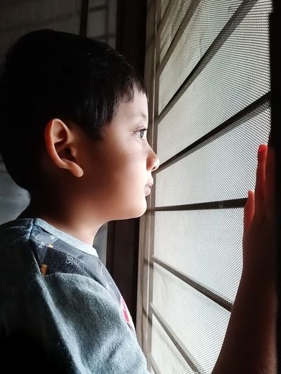 Close-up portrait of boy looking through window