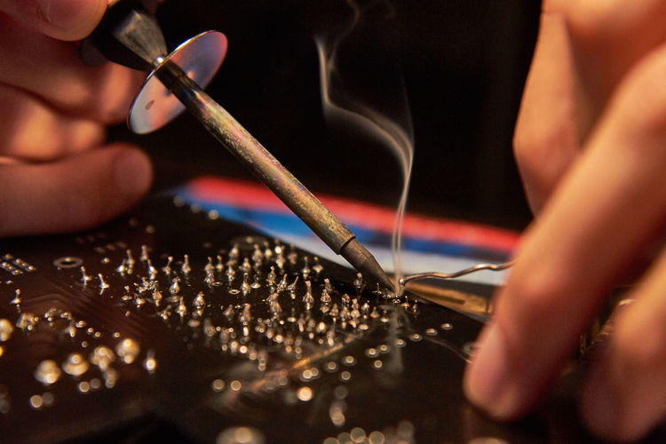 Cropped image of hand soldering electronic circuit board