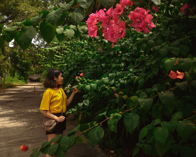 Full length of girl standing by flowering plant