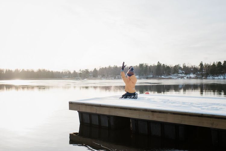 Boy throwing snow up in the air whilst playing by the water in sweden