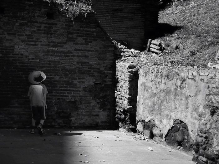 Rear view of man walking on stone wall