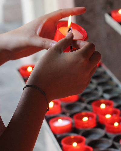 Cropped hands of woman burning candles