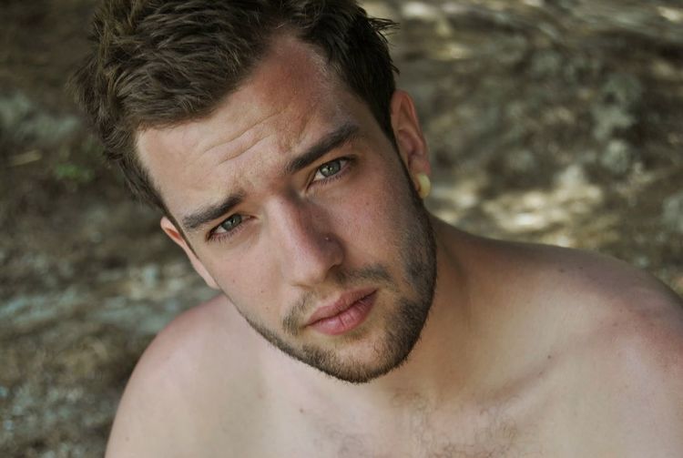 Close-up portrait of shirtless young man