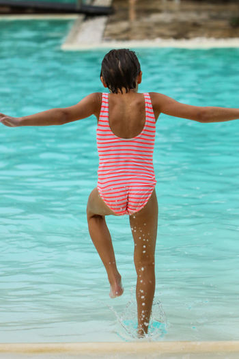 Rear view of girl running in swimming pool