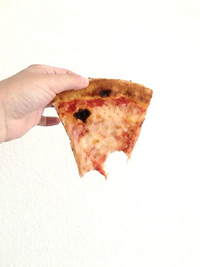 Close-up of hand holding pizza over white background