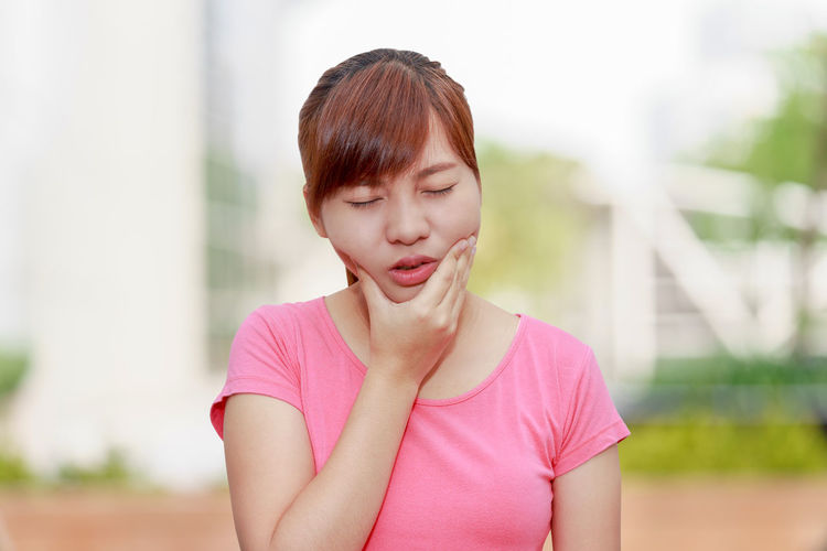 Woman with toothache standing outdoors