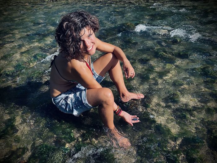 Side view of young woman sitting in water