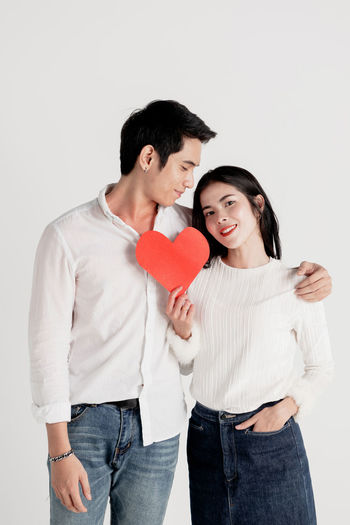 Young couple holding hands against white background