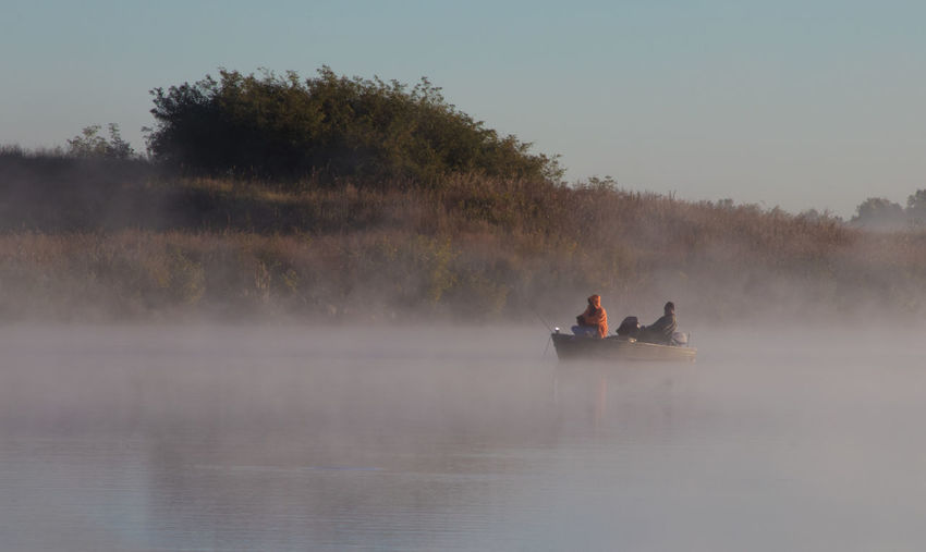 People in boat on lake during foggy weather