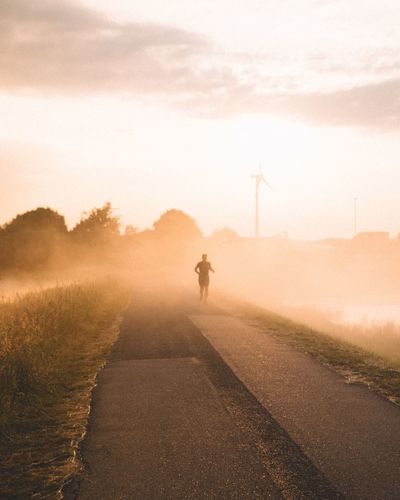 Rear view of man running on road against sky