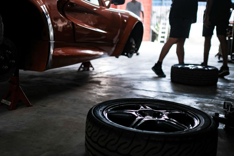 Low view of a classic orange sport car tire change in a garage