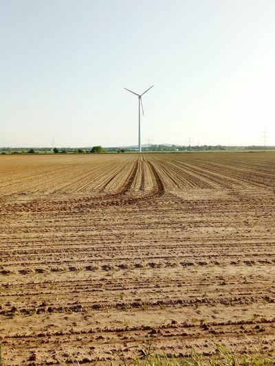 Scenic view of agricultural field against clear sky and windmill