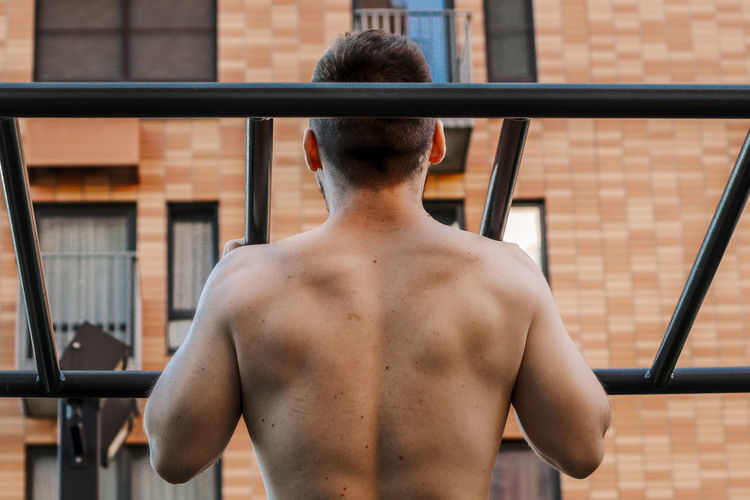 Rear view of shirtless man standing outdoors
