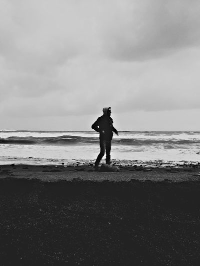 Silhouette man standing at beach against sky