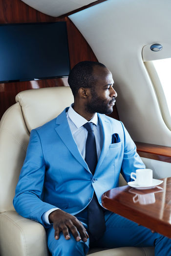 Male entrepreneur looking through window while traveling through airplane