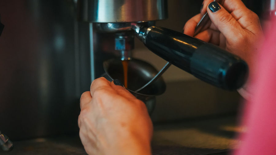 Cropped hand of woman preparing coffee at cafe
