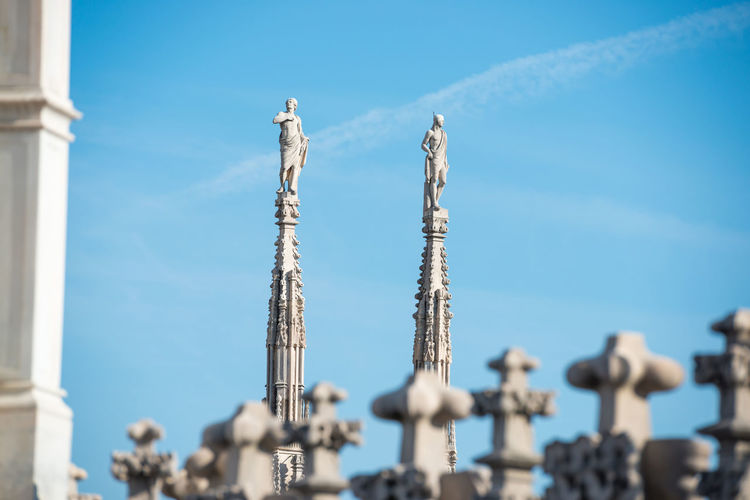 View to spires and statues on roof of duomo through ornate marble fencing. milan, italy